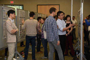 An aisle shoty showing multiple people looking at and presenting information about the posters