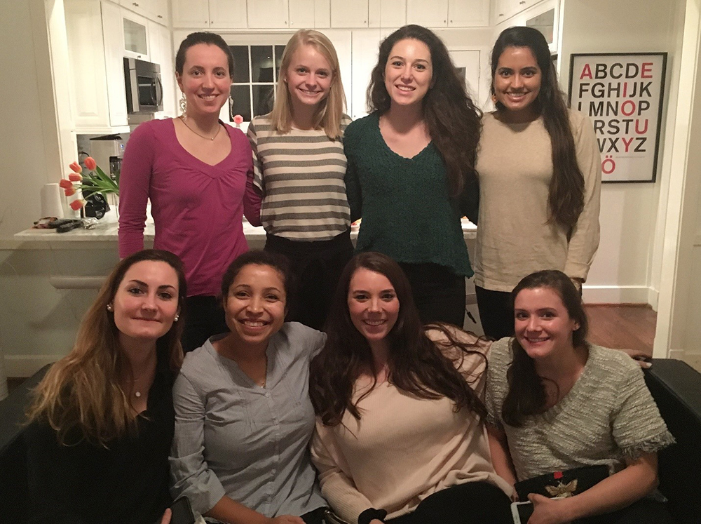 Eight women four standing behind four women sitting all smiling