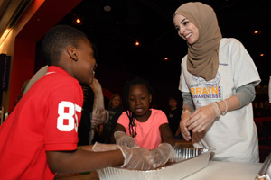 a woman ina brain night t-shirt explaining to a young male child how to pick up a human brain