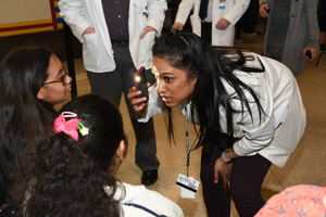 a woman in a white smock taking pictures of children at the exhibit