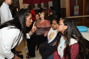 A woman in a white smock lecturing children at the exhibit