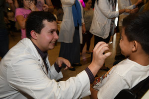 a man in a white smock about to swab a young child