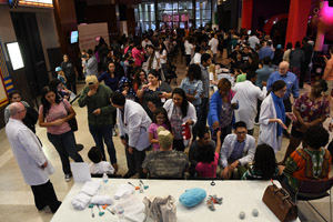 a long shot showing the complete length of the ehibit hall and most of the displays, quite a large crowd is attending