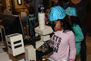 A tween looking through a microscope at a small piece of the human brain.