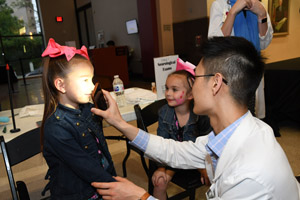  a medical school student experimenting on a child observing pupil contraction under bright light