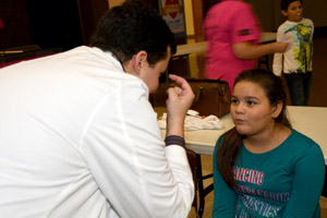 a teenager undergoing an eye tracking experiment being conducted by a man in a lab smock