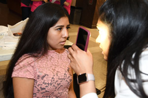 Female teenager interacting with a woman in a white smock with a pink cellphone