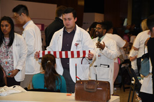 a man in a white smock explaing about a red-white barred piece of cloth