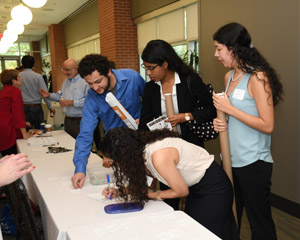 Thre women and a man stading over a table one woman may be filling out a form