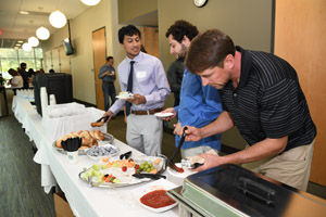 Three men taking advantage of the buffet table.