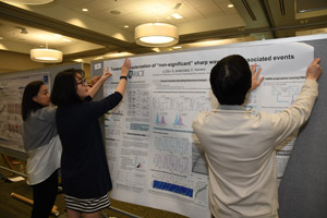 Two women and a man hanging a poster 