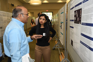 A man with a clipboard and a woman discuss a poster. 