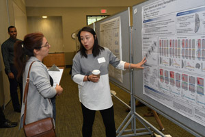 a person (judge) with clipboard having a presentation board explained to her by the woman presenting the board 