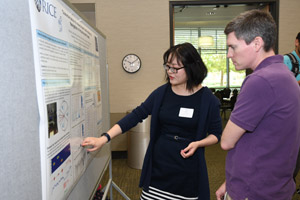 A woman presenting her poster to a man in a purple shirt.