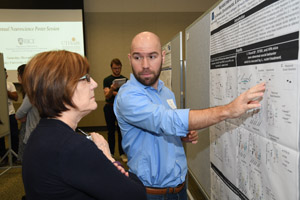 A man explaining his poster to a female