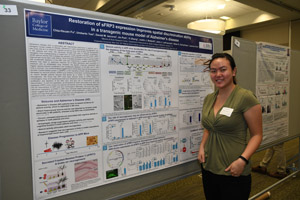 A female student proudly showing off her poster