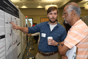 a person (judge) with clipboard having a presentation board explained to him by the man presenting the board