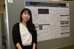 An Asian woman standing proudly beside her poster