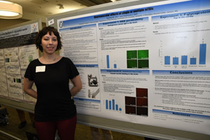 A young woman smiling beside her poster