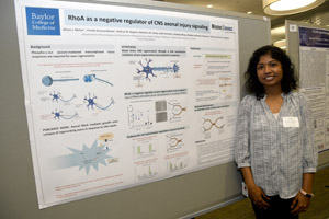 A woman proudly standing beside the poster she is presenting