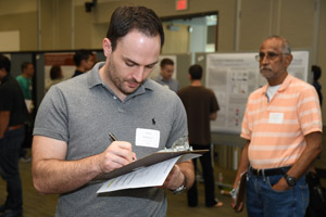 A man with a clipboard apparently judging and scoring a poster.