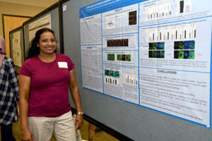 A smiling woman standing proudly beside her poster