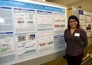 A young Asian student proudly standing by the poster he is presenting.