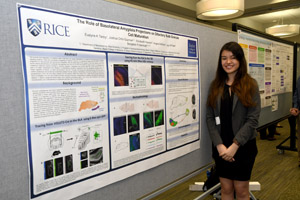 A young woman proudly standing by the poster she is presenting.