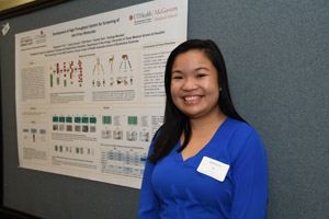 A smiling woman standing beside her poster