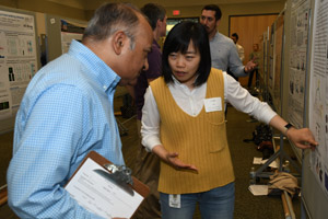 A woman explaining her poster to a man with a clipboard