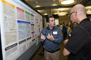 One man presenting his poster to another man.