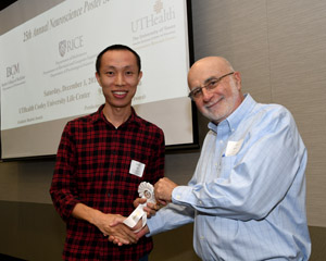 A man presenting a white winner's ribbon to a male poster presentor.