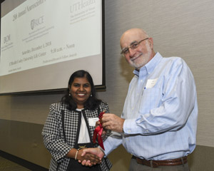 A man presenting a red winner's ribbon to a female