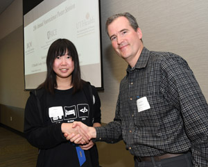 A man presenting a blue winner's ribbon to a female