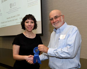 A woman being presented a blue ribbon