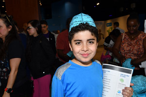 A boy in a blue shirt proudly holding a paper whilst posing for the camera