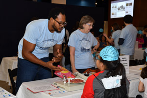 a man and a woman handing out brochures at a table 