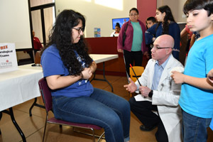 a gentleman performing an experiment on a teenage girl while a small child looks away