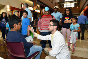a man in a lab smock performing a perception experiment on a male teenager while several people look on.
