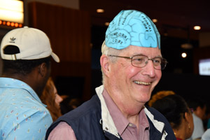 A doctor wearing a blue brain hat smiling broadly for the camera