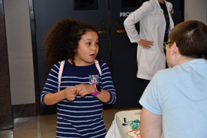 A young female child overjoyed at what a gentleman in a white lab smock has just told her