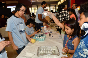 a young girl preparing to drop an egg into a small aluminum tray