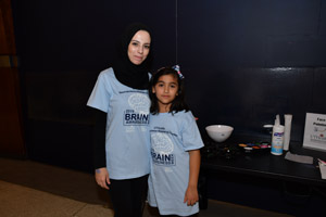 A woman and a young girl posing for the camare in front of a dark wall