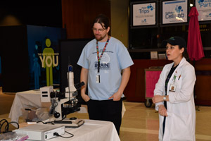 A man and a woman standing near a large microscope