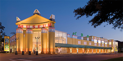 Outside image of the Children's Museum of Houston it's a lovely evening image with subdued lighting, it's relevance to the page is; events are held here for children that tell about how the brain works